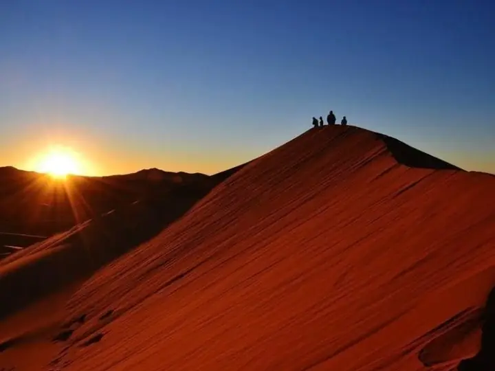 Sun over the crest of a great red dune in Erg Chebbi