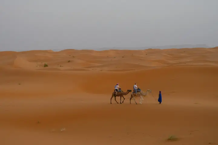 Piccola carovana che attraversa una piana di dune