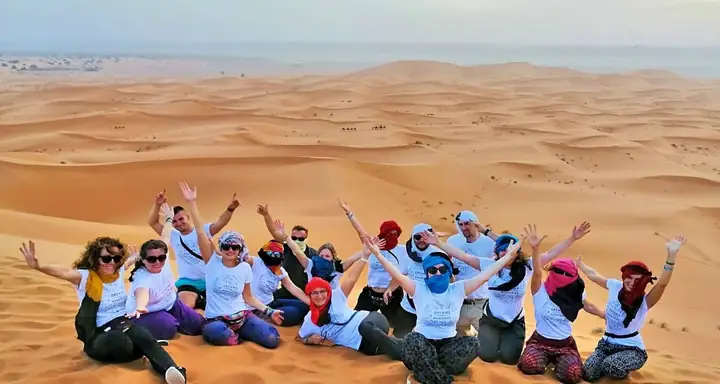 Gruppo di viaggiatori che festeggia fra le dune di Merzouga