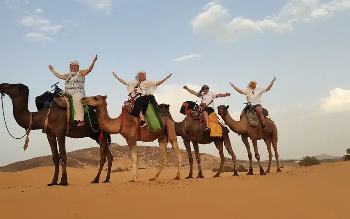 Viaggiatori felici sui loro cammelli nel deserto di Merzouga